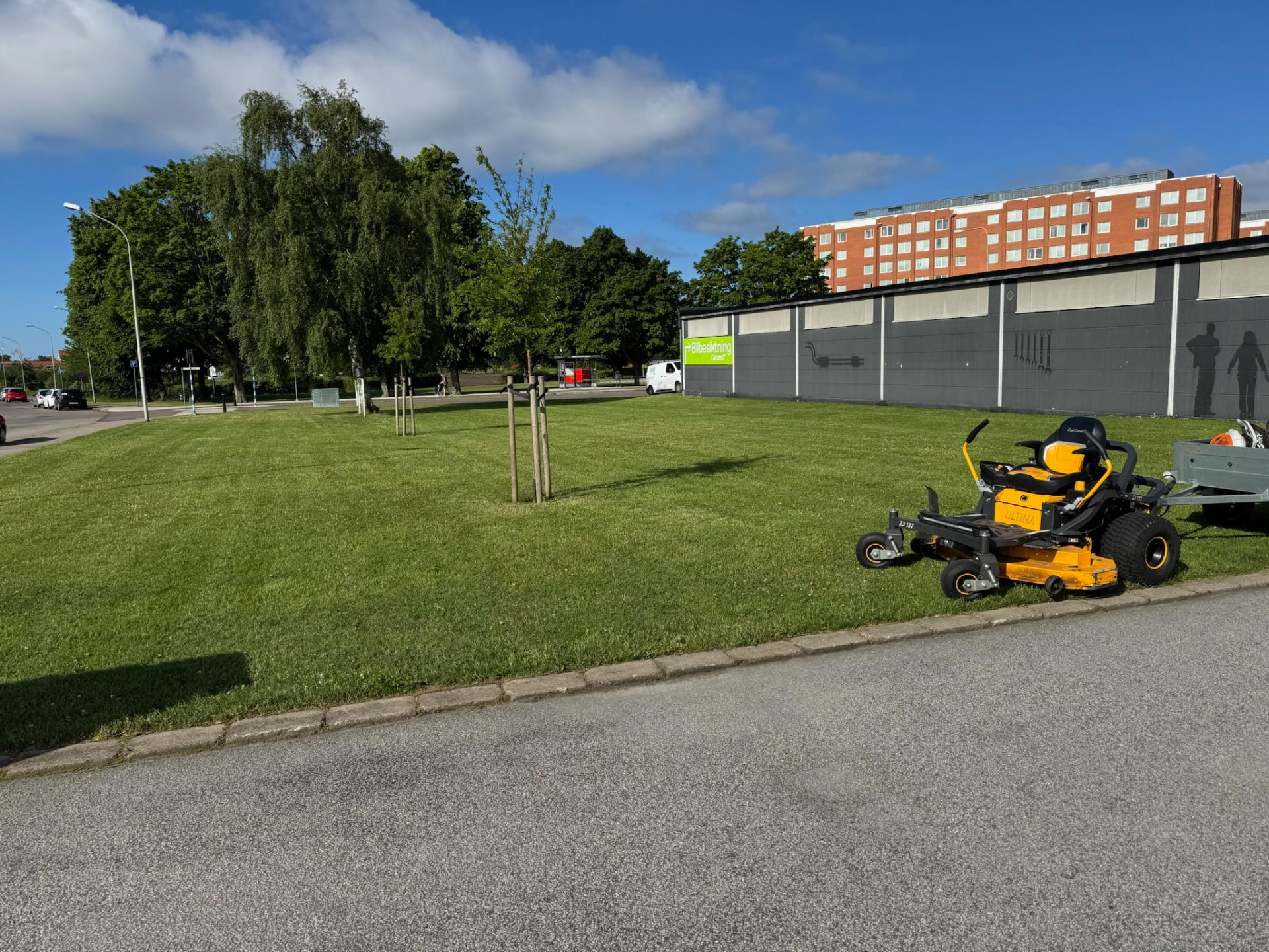 Åkgräsklippare på en stor gräsmatta vid ett bostadshus